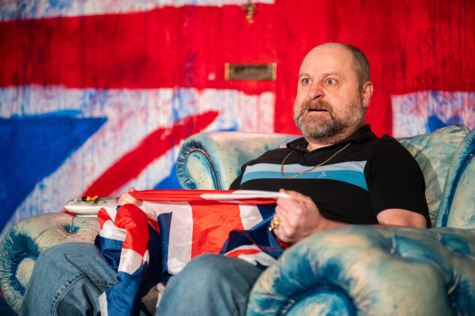 Harry Ward on stage for FLEG, sitting in an armchair holding a Union flag.