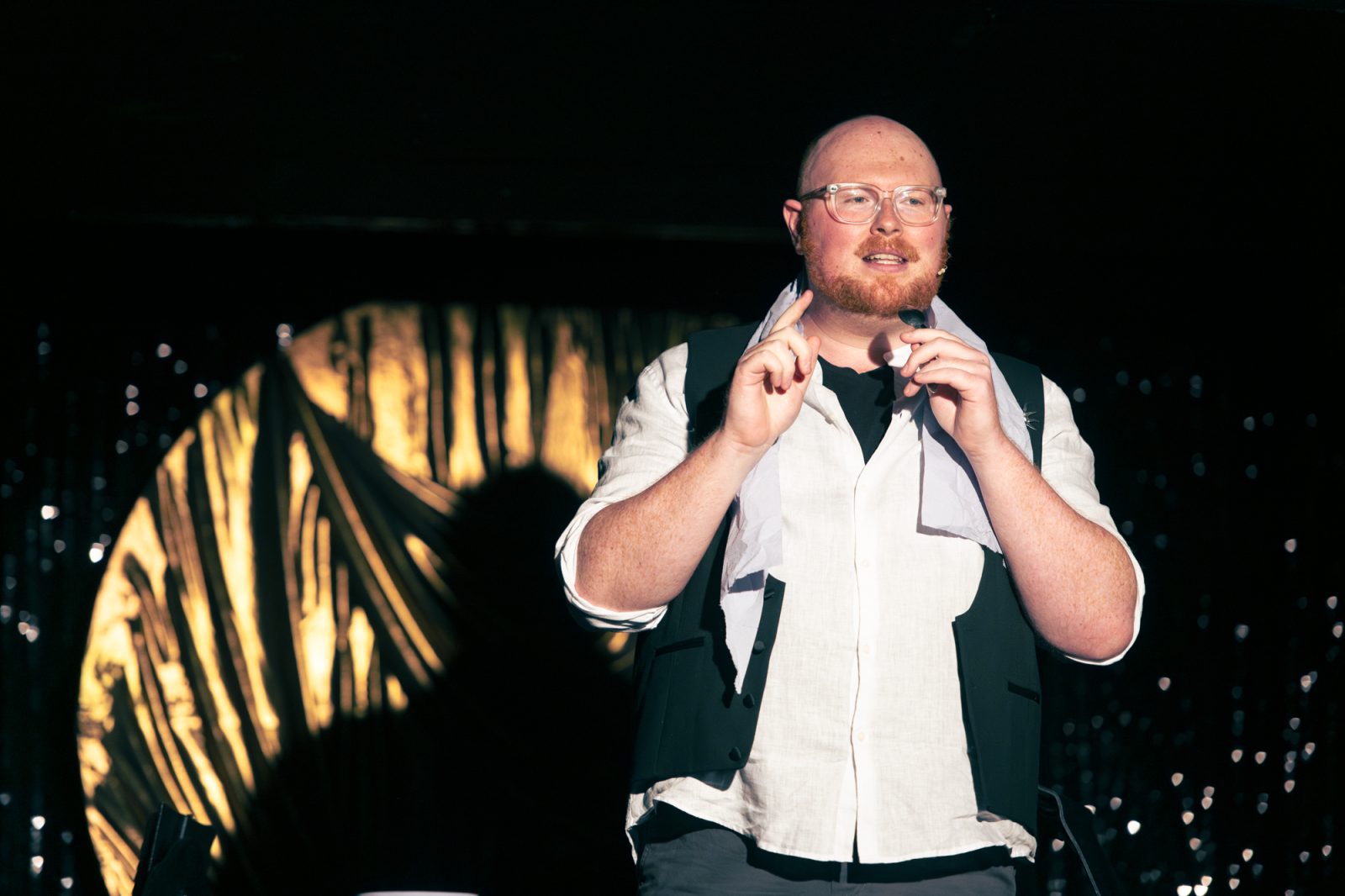 Marc Mackinnon on stage, in a white shirt.