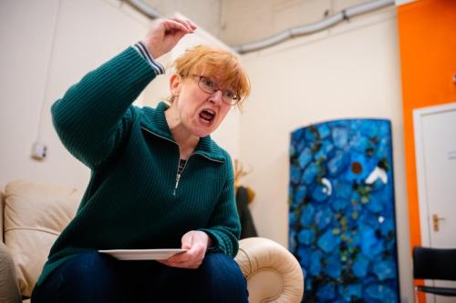Beth Marshall in rehearsals, shouting and raising her right arm into a fist.